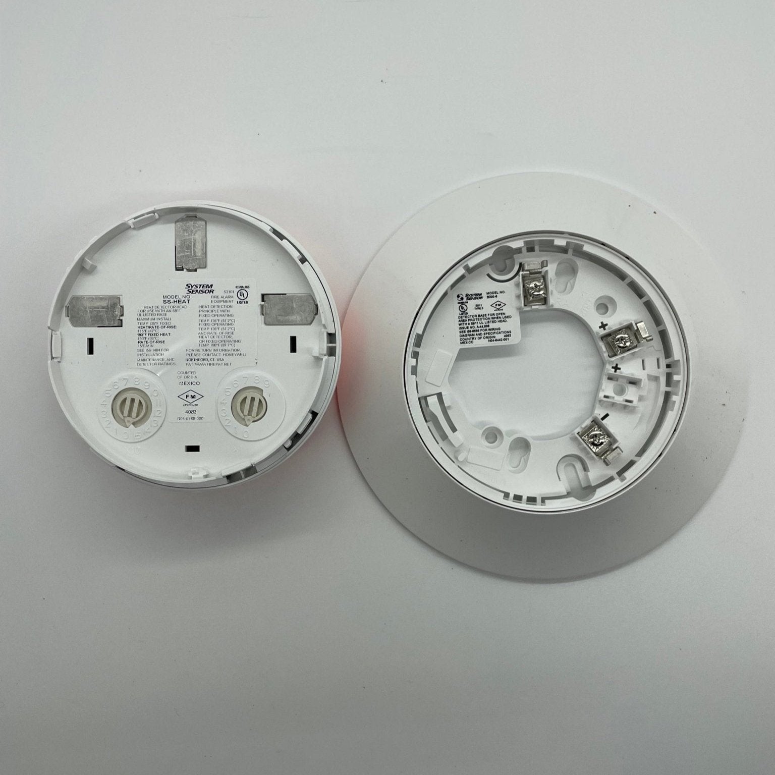 System Sensor SS-HEAT fixed thermal detector for fire detection, showing the white metal housing and sensing element.