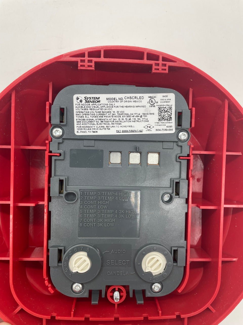 System Sensor CHSCRLED red chime strobe alarm showing a bright red flashing light and chime mechanism.