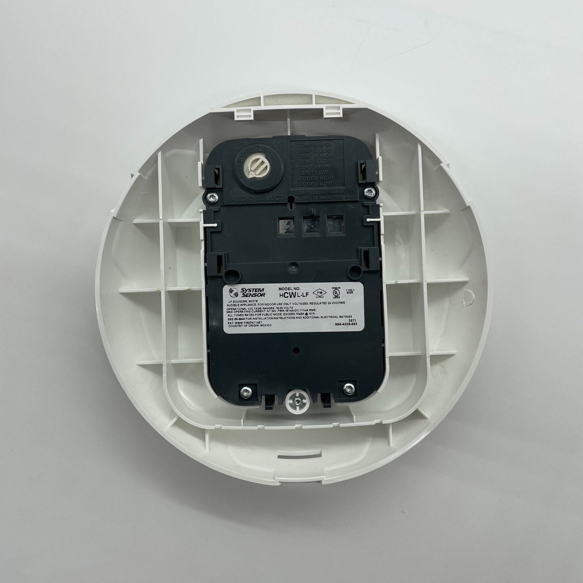 System Sensor HCWL-LF low-frequency compact sounder mounted on a panel, showcasing its design and size for alarm signaling.